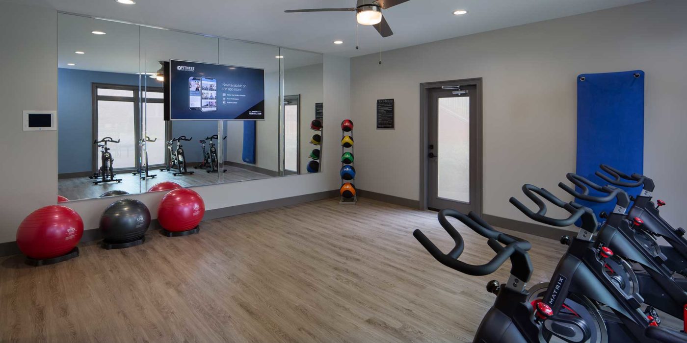 yoga center with pilates balls, tv, mirror, and bikes