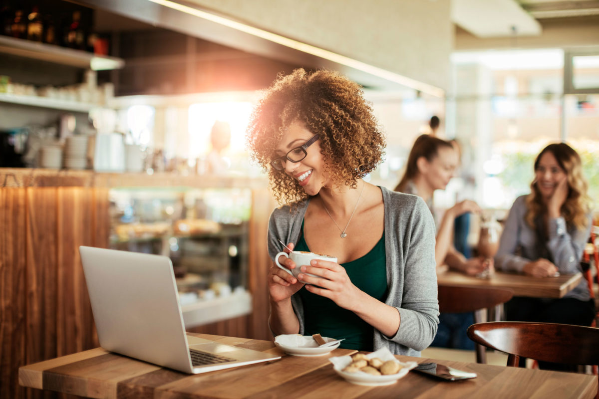 smiling woman at coffee shop with computer drinking coffee